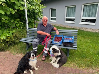 Ein Mann sitzen auf der Bank mit zwei Hunden an der Leine.