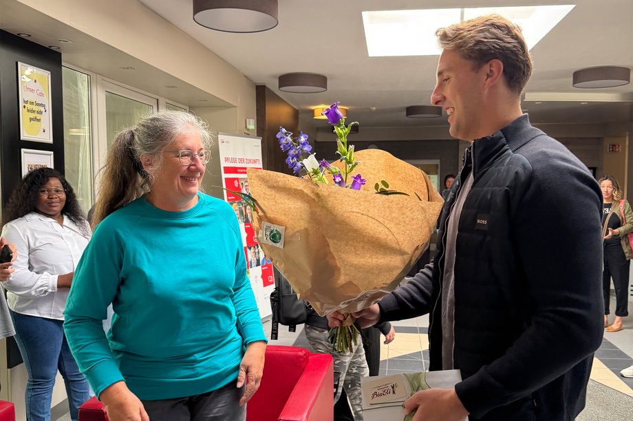 Einrichtungsleitung überreicht an eine Mitarbeiterin zum Dienstjubiläum 25 Jahre einen Blumenstrauß