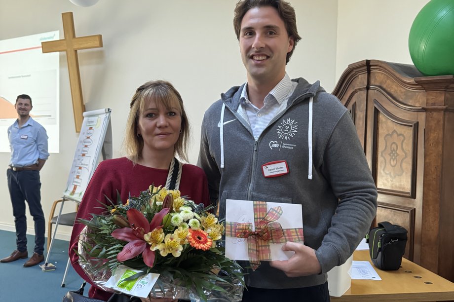 Einrichtungsleiter überreicht Mitarbeiterin einen Blumenstrauß