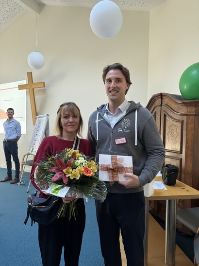 Einrichtungsleiter überreicht Mitarbeiterin einen Blumenstrauß