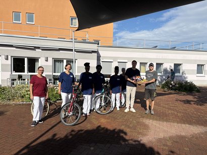 Auszubildende und Mitarbeitende präsentieren vor einer Pflegeeinrichtung gespendete Fahrräder des Bauhofs zur Förderung nachhaltiger Mobilität