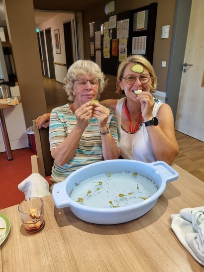 Alltagsbegleiterin und Bewohnerin kühlen sich mit Kräuterbädern ab.