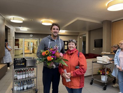 Die Einrichtungsleitung überreicht zum Dienstjubiläum einen bunten Blumenstrauß